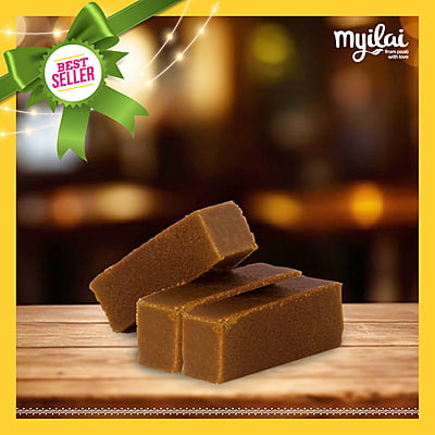 Three blocks of Karupatti Mysore Pak on a wooden table, tagged as "Best Seller" from Myilai Sweets.