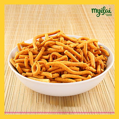 A bowl of Millet Kara Sev is placed on a wooden table with myilai logo on top A bowl of Millet Kara Sev is placed on a wooden table with myilai logo on top